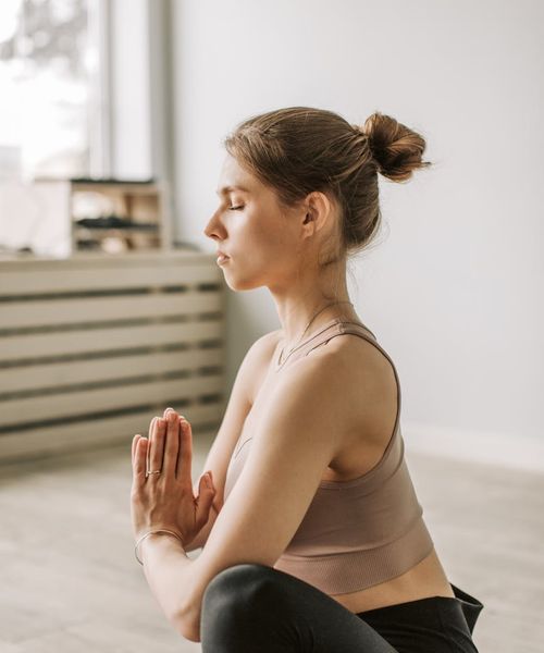 Woman performing a calm and focused yoga pose in a dark, serene environment.